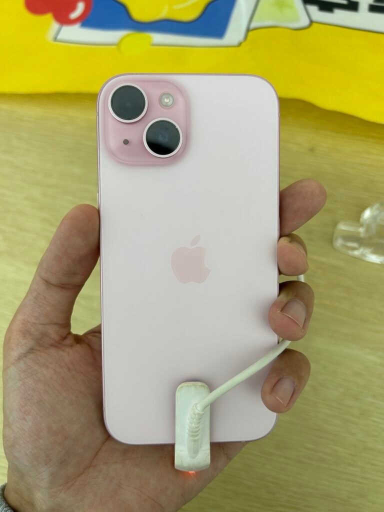 iPhone 15 rosa na mão de um a pessoa na loja