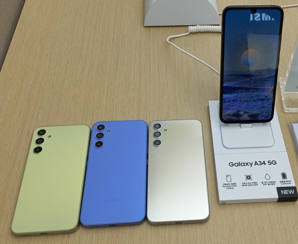 Galaxy A34 on store displaing screen and three deviced from back view in many colors