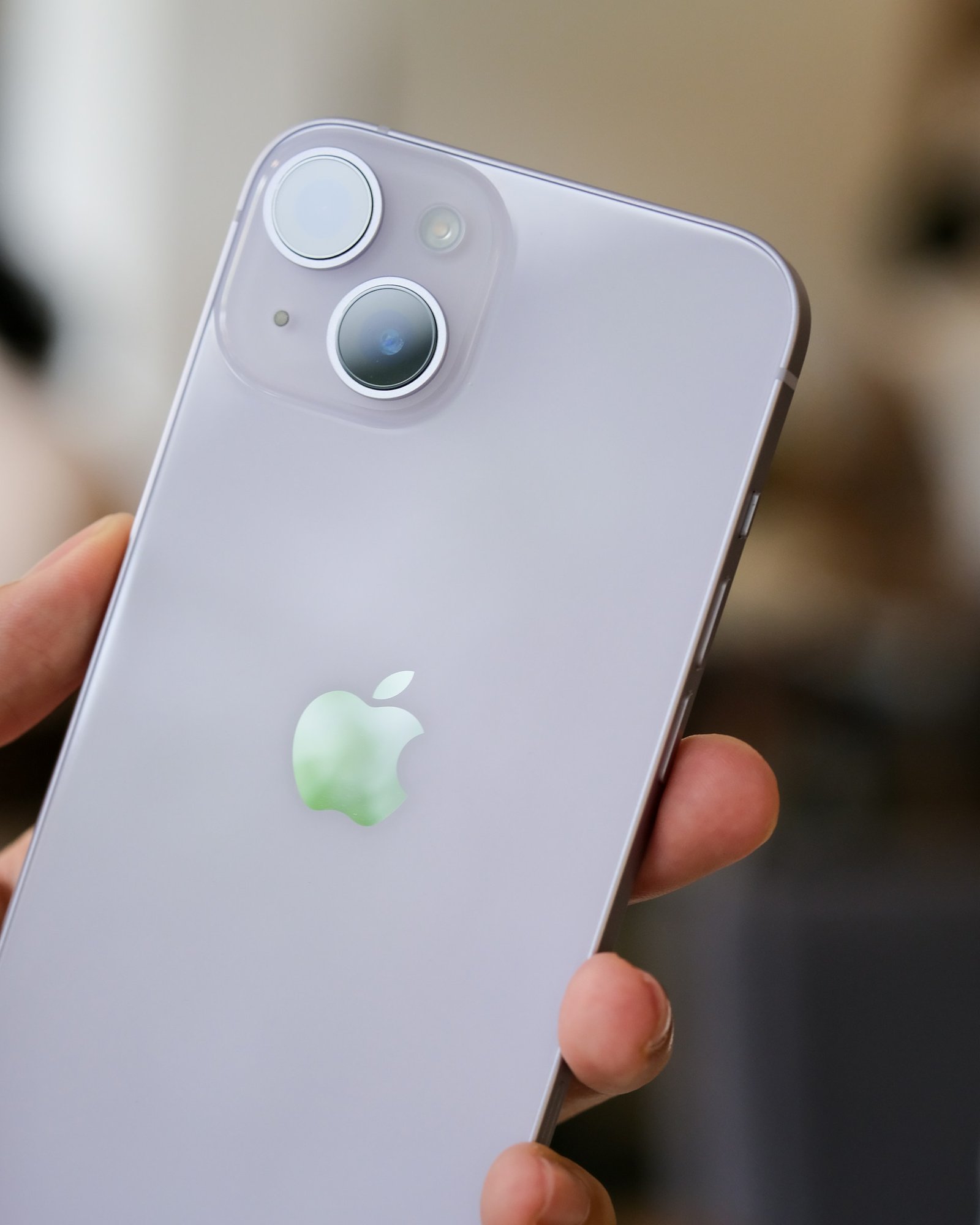 iPhone 14 em mãos com fundo desfocado